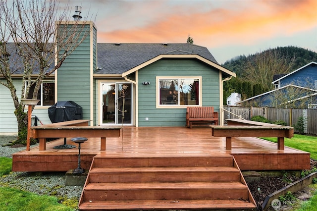 deck at dusk with area for grilling and fence