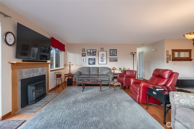 living area with a fireplace, wood finished floors, and baseboards