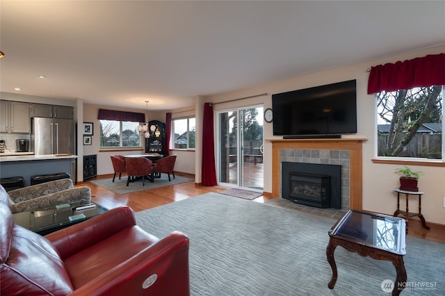 living area featuring light wood-type flooring, a fireplace, baseboards, and recessed lighting