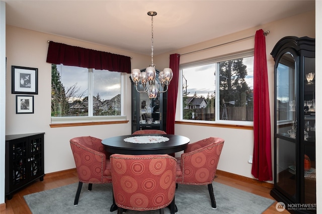 dining area featuring a notable chandelier, baseboards, and wood finished floors