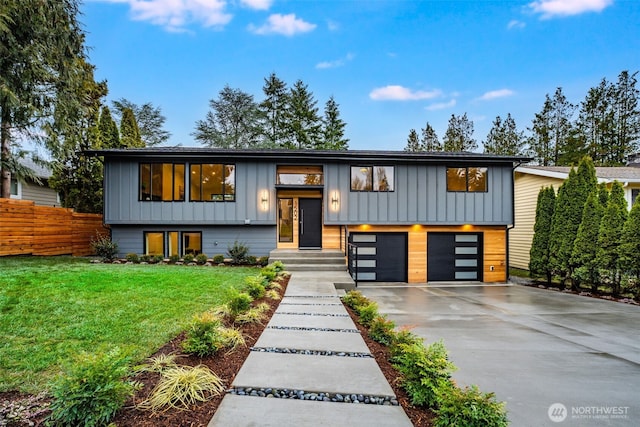 split foyer home with an attached garage, fence, board and batten siding, and concrete driveway