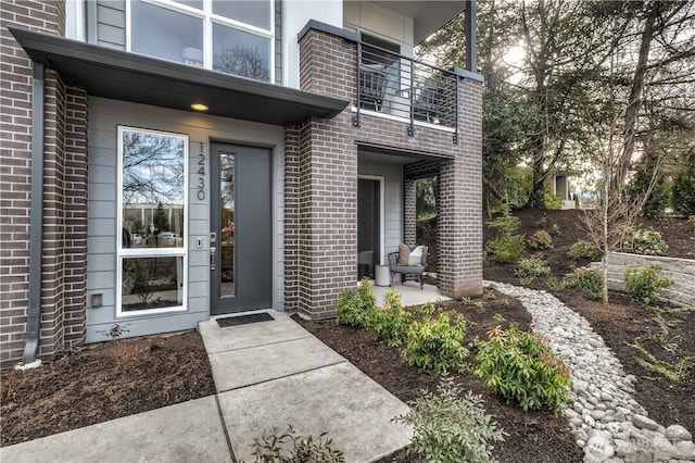 property entrance featuring brick siding and a balcony