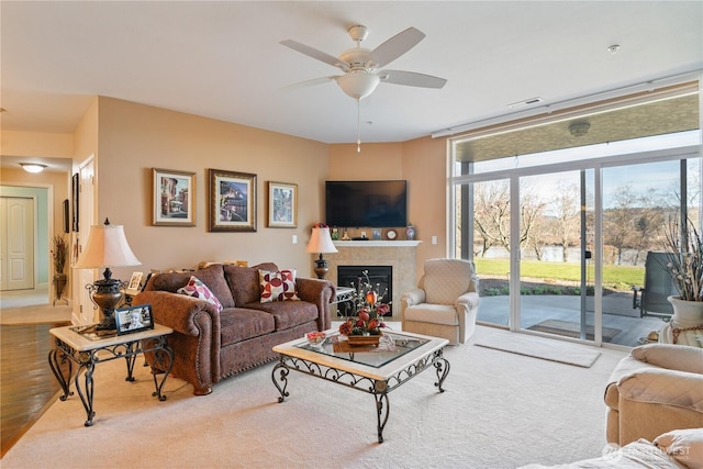 living room with expansive windows, a fireplace, visible vents, and a ceiling fan