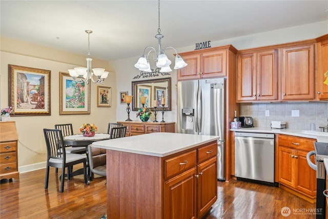 kitchen with dark wood-type flooring, light countertops, appliances with stainless steel finishes, decorative backsplash, and an inviting chandelier