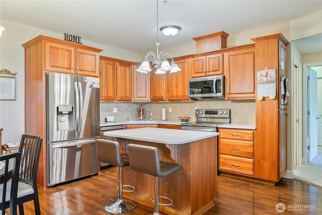 kitchen featuring light countertops, appliances with stainless steel finishes, dark wood-style flooring, and tasteful backsplash