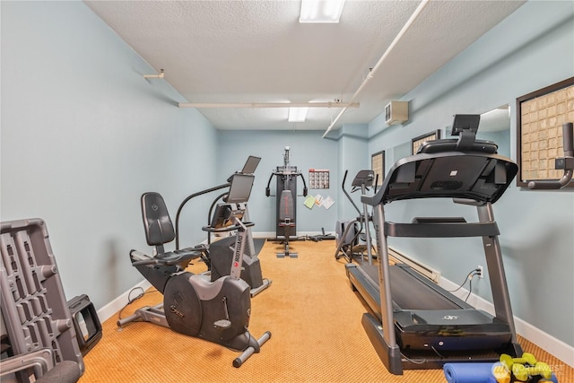 exercise area with carpet floors, a textured ceiling, and baseboards