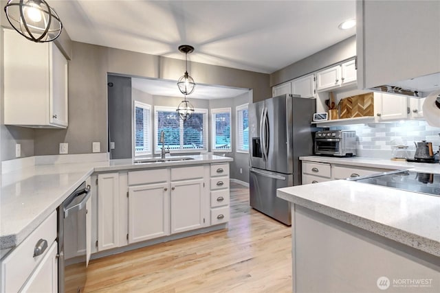 kitchen featuring a toaster, white cabinets, stainless steel appliances, light wood-type flooring, and a sink