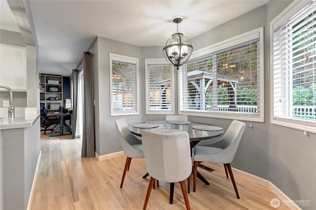 dining area featuring a notable chandelier, light wood-style flooring, and baseboards