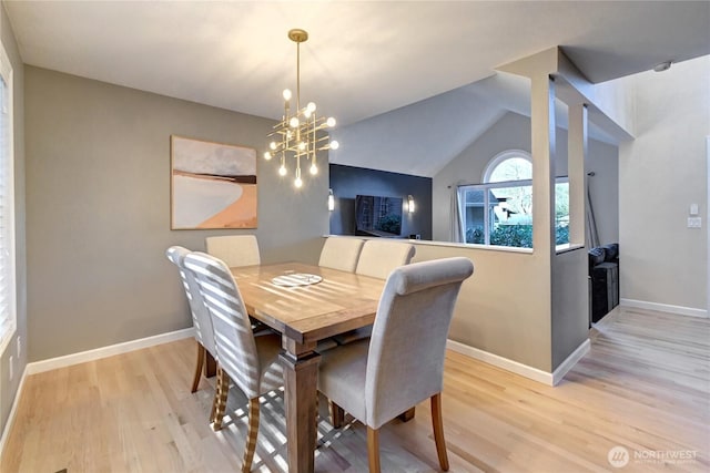 dining room featuring a chandelier, vaulted ceiling, light wood-type flooring, and baseboards