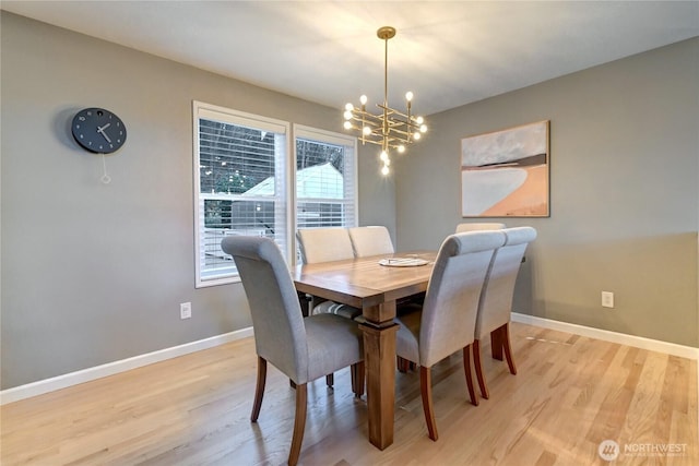 dining room featuring light wood-style flooring, baseboards, and an inviting chandelier