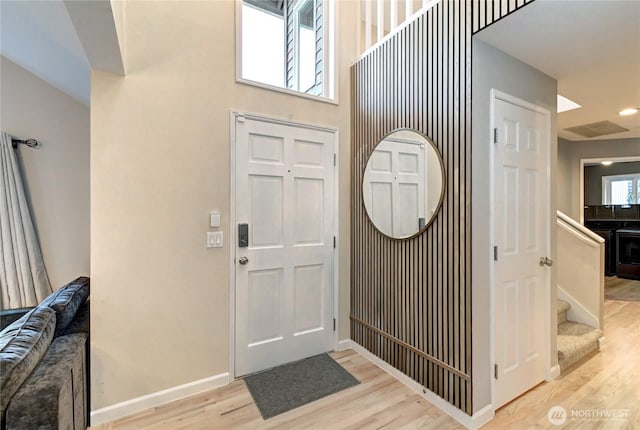 entrance foyer featuring stairway, visible vents, baseboards, and wood finished floors