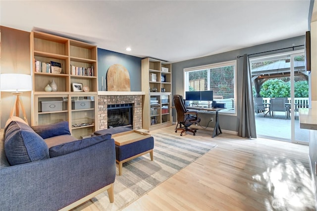 living area featuring a brick fireplace, baseboards, wood finished floors, and recessed lighting