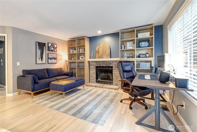 office space featuring a brick fireplace, wood finished floors, and baseboards