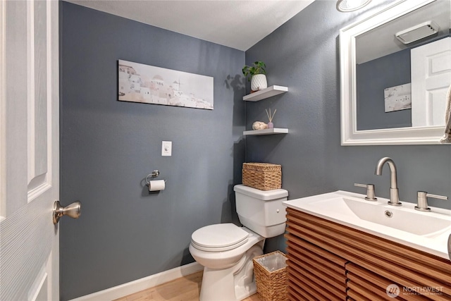 bathroom featuring toilet, baseboards, and vanity