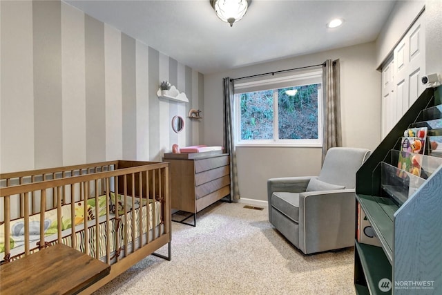 bedroom featuring recessed lighting, light colored carpet, baseboards, a nursery area, and wallpapered walls