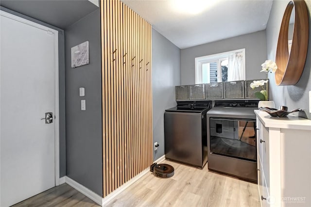 washroom with light wood-type flooring, laundry area, independent washer and dryer, and baseboards