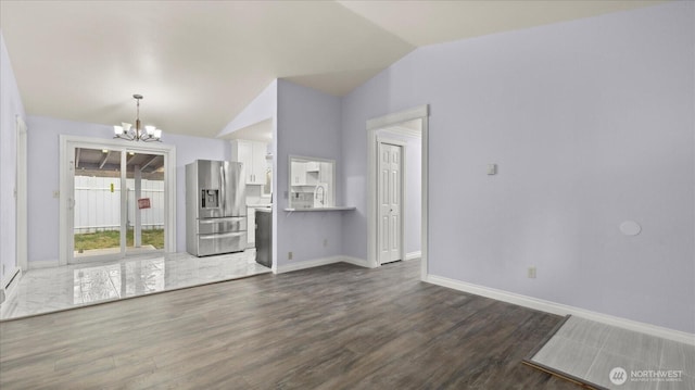 unfurnished living room featuring dark wood-style floors, baseboards, vaulted ceiling, and a notable chandelier