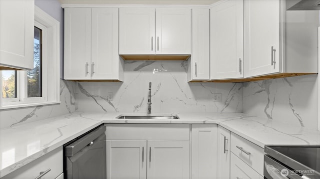 kitchen with stainless steel appliances, a sink, white cabinetry, backsplash, and light stone countertops