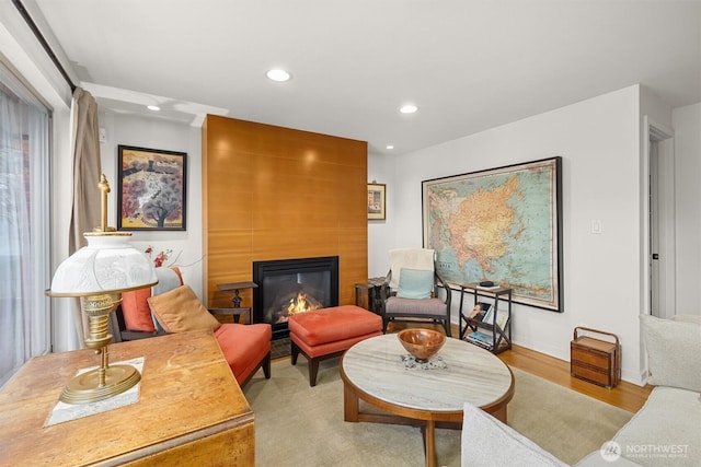 sitting room with a large fireplace, baseboards, wood finished floors, and recessed lighting