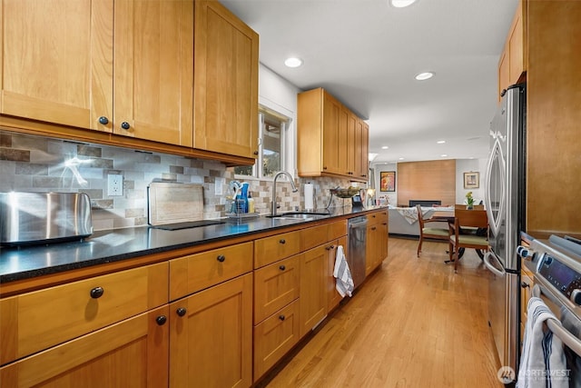 kitchen with recessed lighting, stainless steel appliances, a sink, light wood-type flooring, and tasteful backsplash