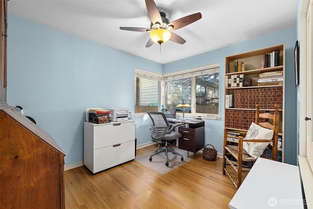 office space with baseboards, ceiling fan, and light wood finished floors