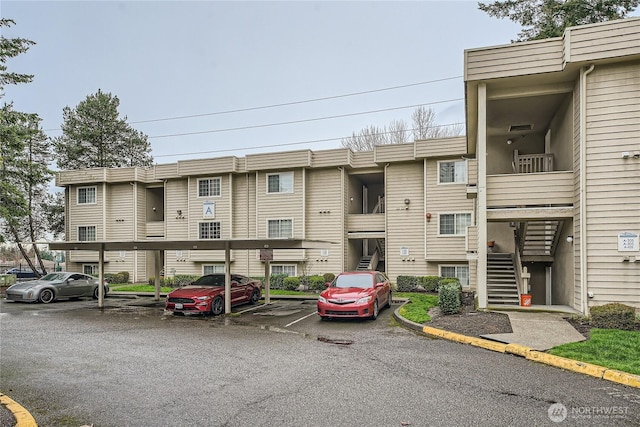 view of property featuring stairway and covered and uncovered parking