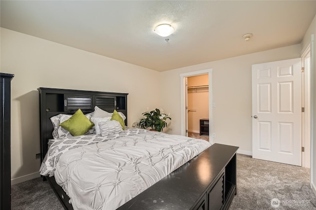 carpeted bedroom featuring a spacious closet and baseboards