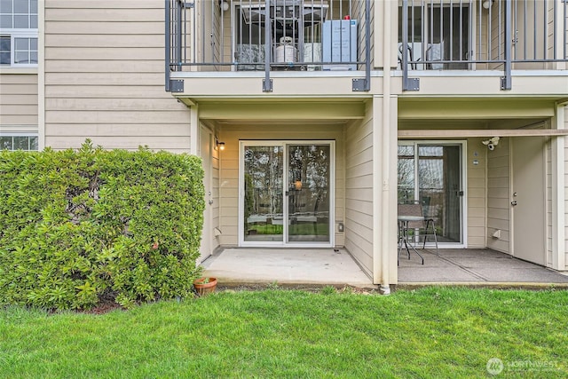 entrance to property featuring a balcony, a patio area, and a lawn