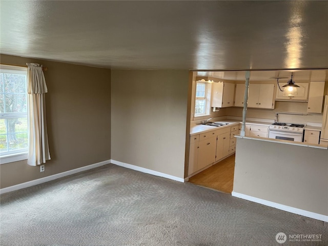 kitchen featuring white gas range, baseboards, light countertops, and a sink