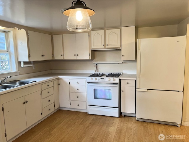 kitchen featuring light wood finished floors, light countertops, white appliances, and a sink