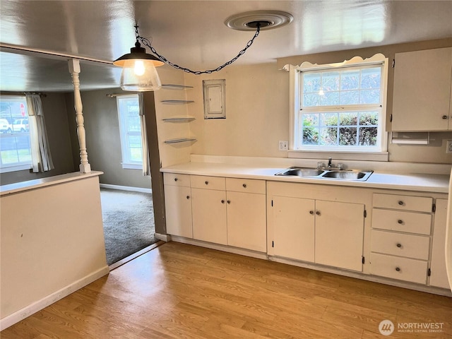 kitchen featuring light countertops, plenty of natural light, a sink, and light wood-style floors