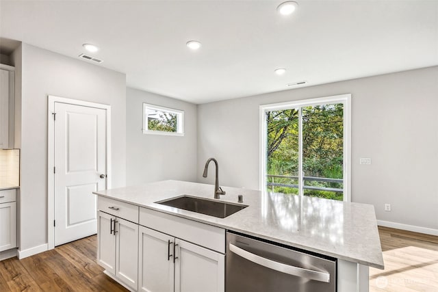 kitchen featuring visible vents, dishwasher, wood finished floors, light stone countertops, and a sink