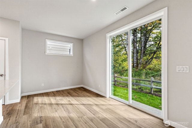 empty room featuring a healthy amount of sunlight, baseboards, and wood finished floors