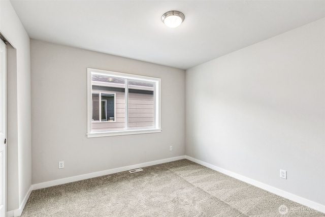 spare room featuring carpet, visible vents, and baseboards