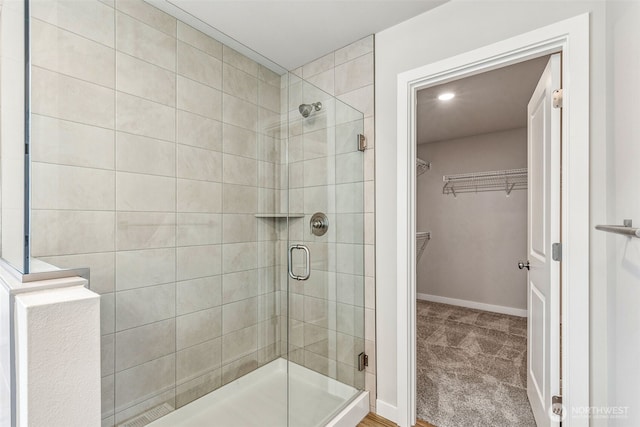 full bath with a stall shower, a spacious closet, and baseboards