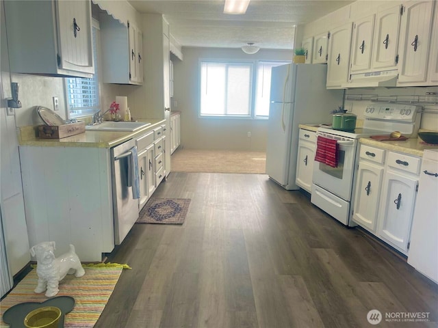 kitchen with light countertops, white appliances, a sink, and white cabinetry