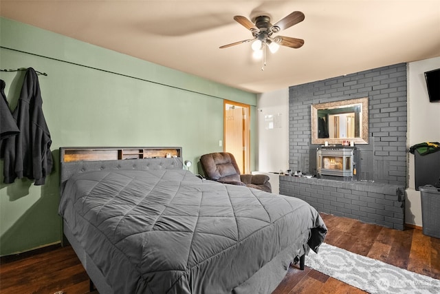 bedroom featuring a fireplace, wood finished floors, and a ceiling fan