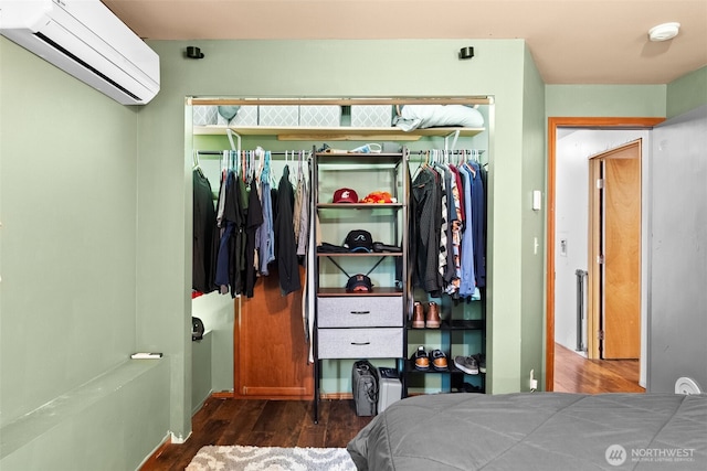 bedroom with an AC wall unit, a closet, and wood finished floors