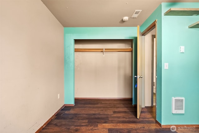 unfurnished bedroom featuring a closet, wood finished floors, visible vents, and baseboards