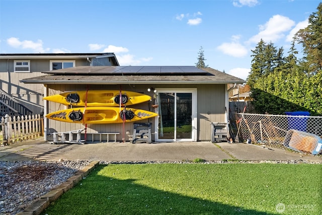 back of property featuring a yard, a patio, fence, and roof mounted solar panels