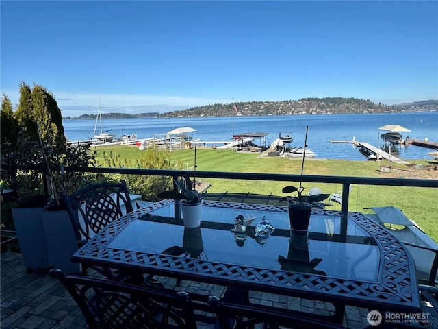 exterior space featuring outdoor dining space, a water view, and a lawn