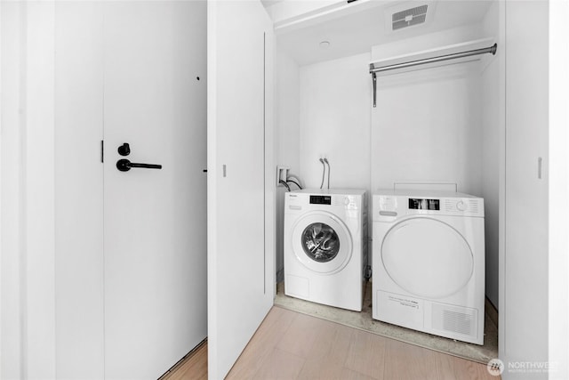 laundry area with washer and clothes dryer, visible vents, laundry area, and light wood-style floors