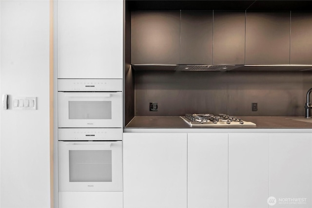 kitchen with modern cabinets, a sink, stainless steel gas stovetop, white cabinets, and white double oven