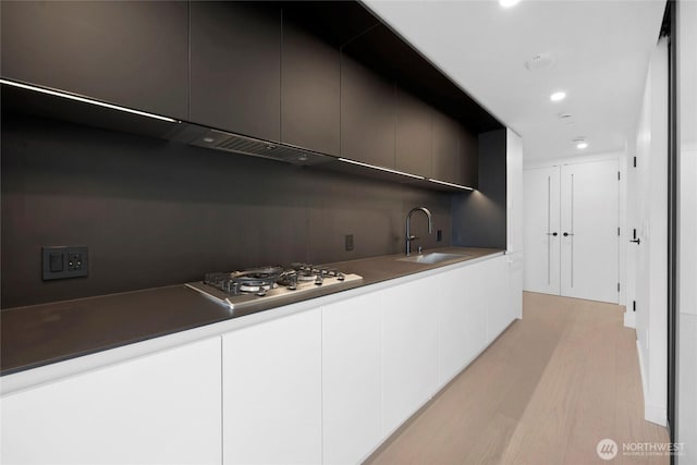 kitchen with stainless steel gas cooktop, modern cabinets, light wood-style floors, and a sink