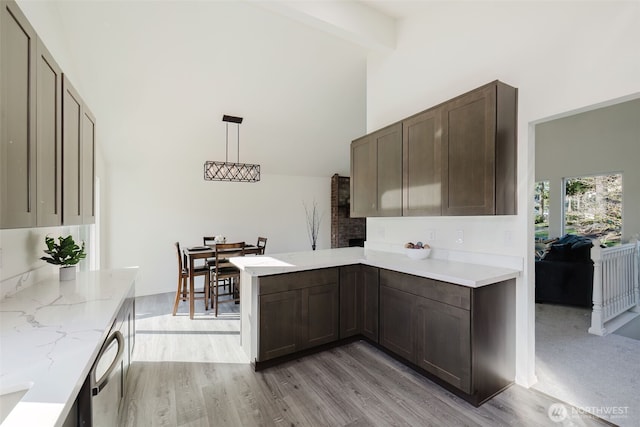 kitchen with dishwasher, light stone counters, a peninsula, light wood-style floors, and high vaulted ceiling