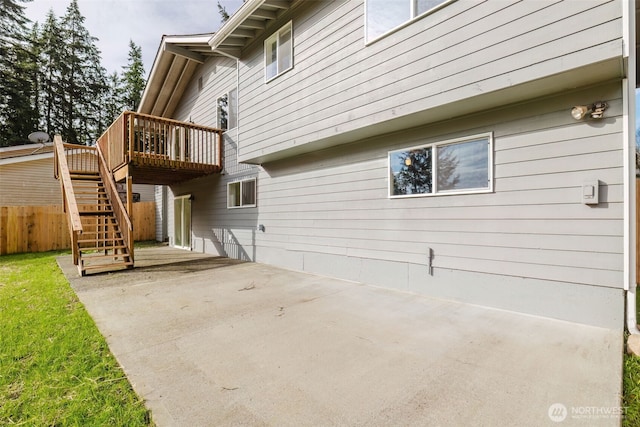 view of side of home featuring a deck, a patio area, fence, and stairway