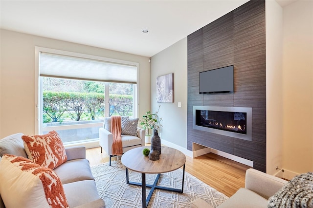 living area with baseboards, a fireplace, and light wood-style floors