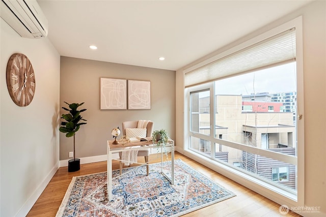 office area featuring a wall unit AC, baseboards, wood finished floors, and recessed lighting