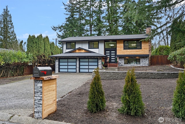 view of front of property with a fenced front yard, a chimney, a garage, stone siding, and driveway