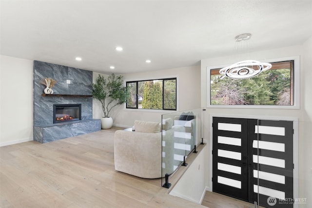 interior space featuring a premium fireplace, baseboards, wood finished floors, and recessed lighting